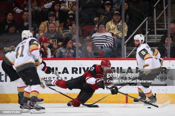 Alex Galchenyuk of the Arizona Coyotes falls as he attempts to control the puck ahead of Deryk Engelland of the Vegas Golden Knights during the...