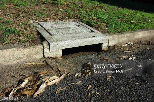 concrete gutter and sewer drain on a suburban road - manhole stock pictures, royalty-free photos & images