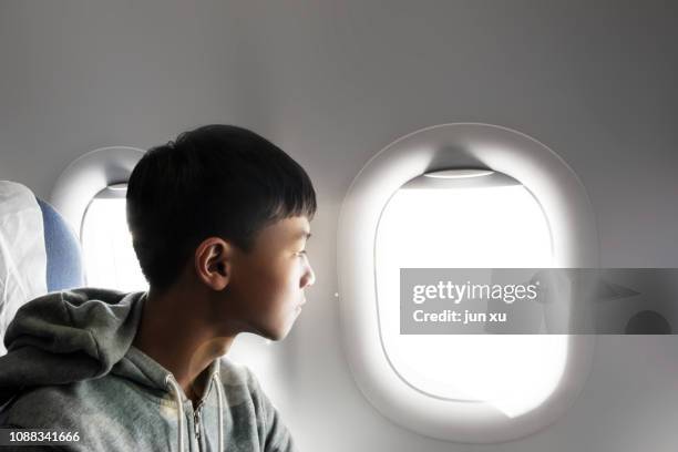 the boy looked out of the plane window at the view - 飛行機の座席 ストックフォトと画像