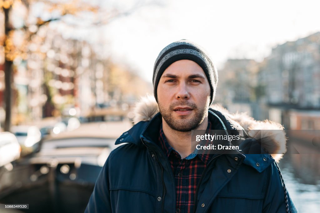 Portrait of handsome guy in winter in Amsterdam near canal