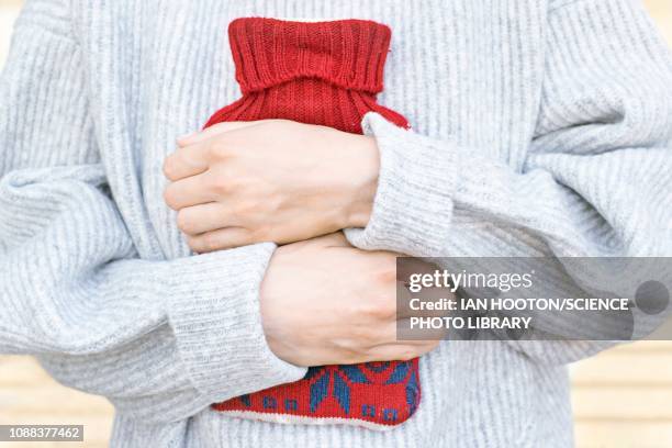woman holding hot water bottle - wärmflasche stock-fotos und bilder