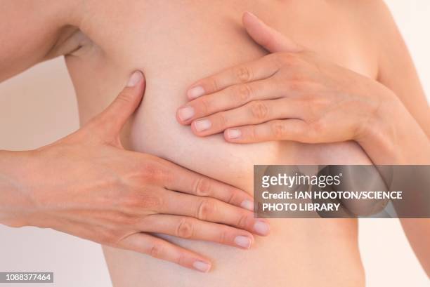young woman examining her breast - seno foto e immagini stock