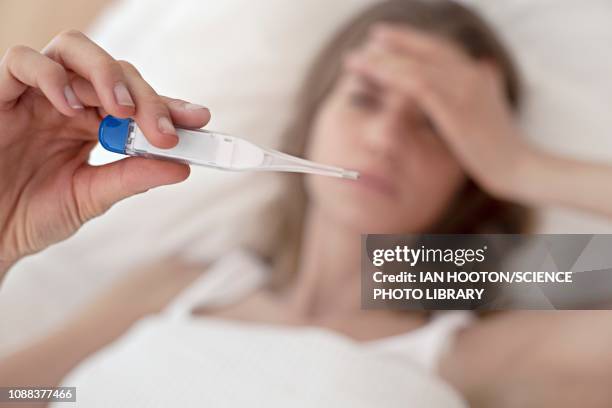 young woman taking her temperature - fever fotografías e imágenes de stock