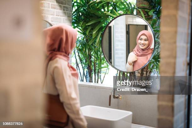 muslim woman with fixing hijab and drying her hands in restroom - vintage hand mirror stock pictures, royalty-free photos & images
