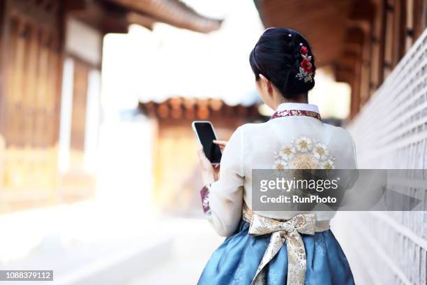 woman in korean traditional clothes using smartphone - south corea foto e immagini stock