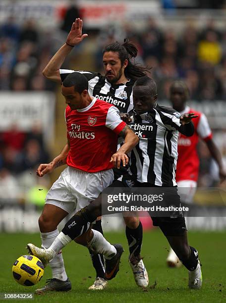 Theo Walcott of Arsenal holds off Jonas Gutierrez and Cheik Tiote of Newcastle during the Barclays Premier League match between Newcastle United and...