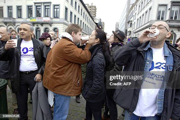 Demonstrators hold plastic cups during the '10:23 Challenge', on February 5 in Brussels. Protesters from more than 23 cities in 10 countries gather...