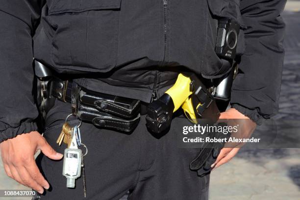 Police officer with a taser gun on his duty belt stands in the plaza in front of The Alamo in San Antonio, Texas.