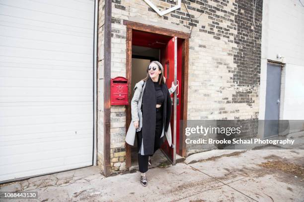 woman exiting a building - woman walking out door stock-fotos und bilder