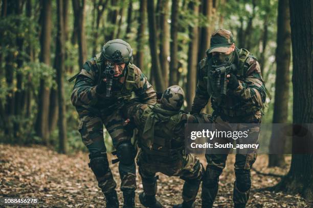 soldiers carrying injured man - wilderness rescue stock pictures, royalty-free photos & images