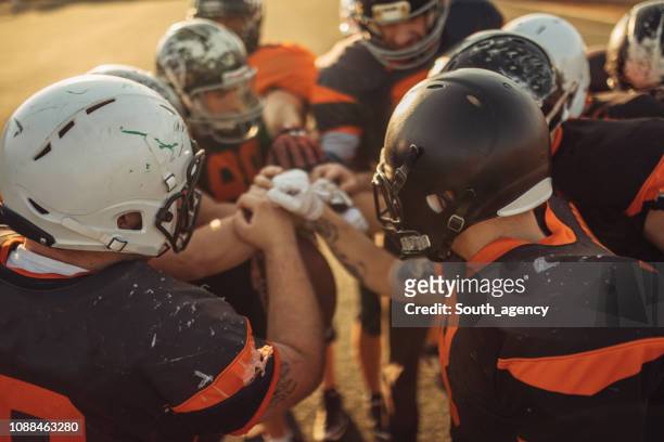 jugadores de fútbol americano acurrucados - huddles in sport fotografías e imágenes de stock