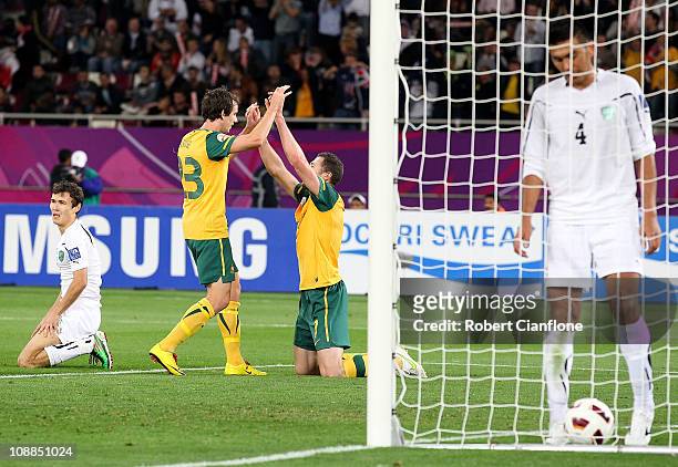 Brett Emerton of Australia celebrates his goal with Robbie Kruse and Aziz Ibragimov and Azur Ismailov of Uzbekistan look dejected during the AFC...