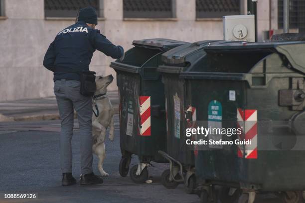 Anti-explosive policemen and a anti-explosive dog approach a trash can to check during a false alarm bomb package for a suspicious bag in Porta...