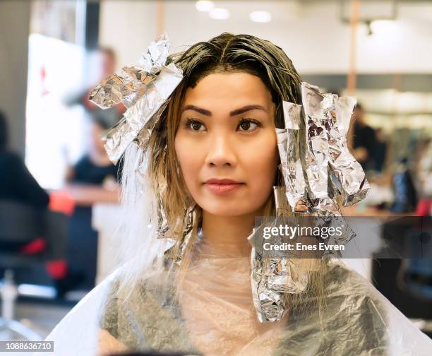 asian woman having hair coloring process in a hair salon - hair coloring stock pictures, royalty-free photos & images