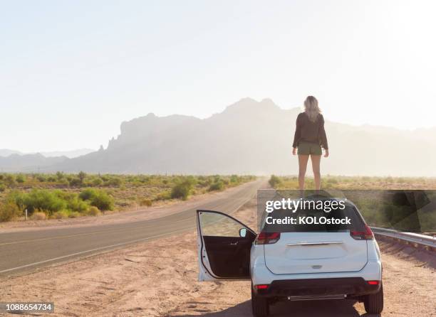 woman stood on car roof watching the sunrise - superstition mountains fotografías e imágenes de stock