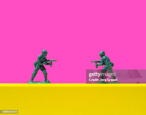 two toy soldiers pointing guns at each other - toy soldier stock pictures, royalty-free photos & images