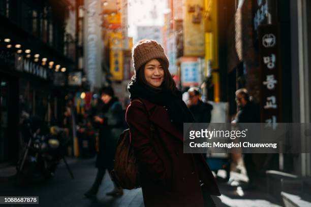 young asian woman traveler traveling with happiness and shopping in myeongdong street market at seoul, south korea. - native korean stock-fotos und bilder