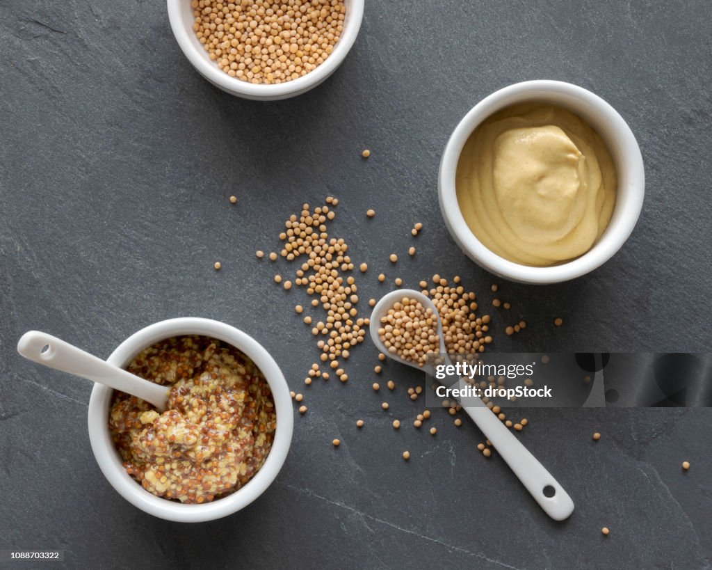 Two kinds of mustard and mustard seeds, top view of jars of mustard