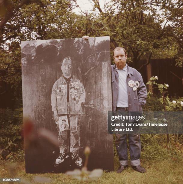 English pop artist, Peter Blake, with a monochrome version of his 1961 painting, 'Self Portrait with Badges', in the garden of his home in Chiswick,...