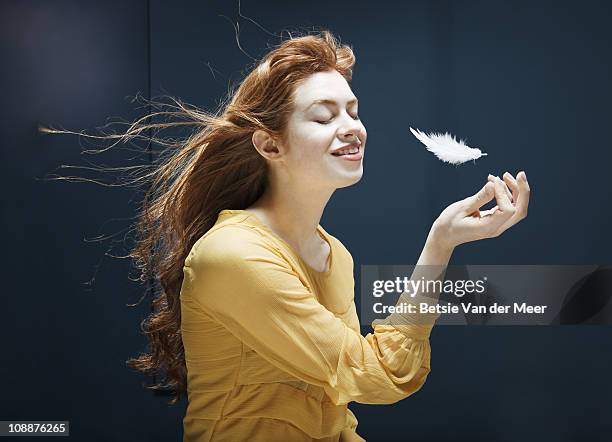 woman lets go of feather blowing in wind. - feather floating stock pictures, royalty-free photos & images