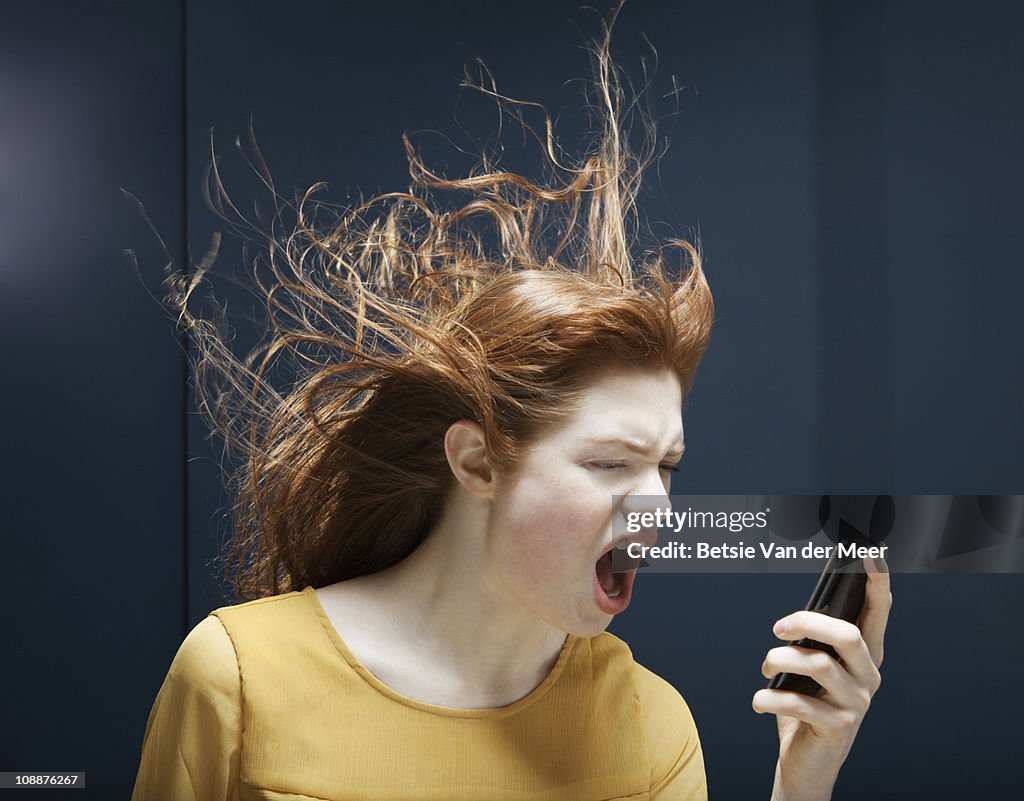 Woman is shouting into phone.