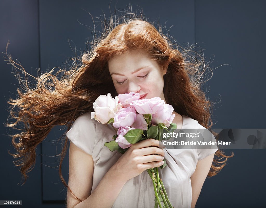 Woman holding and smelling bunch of roses