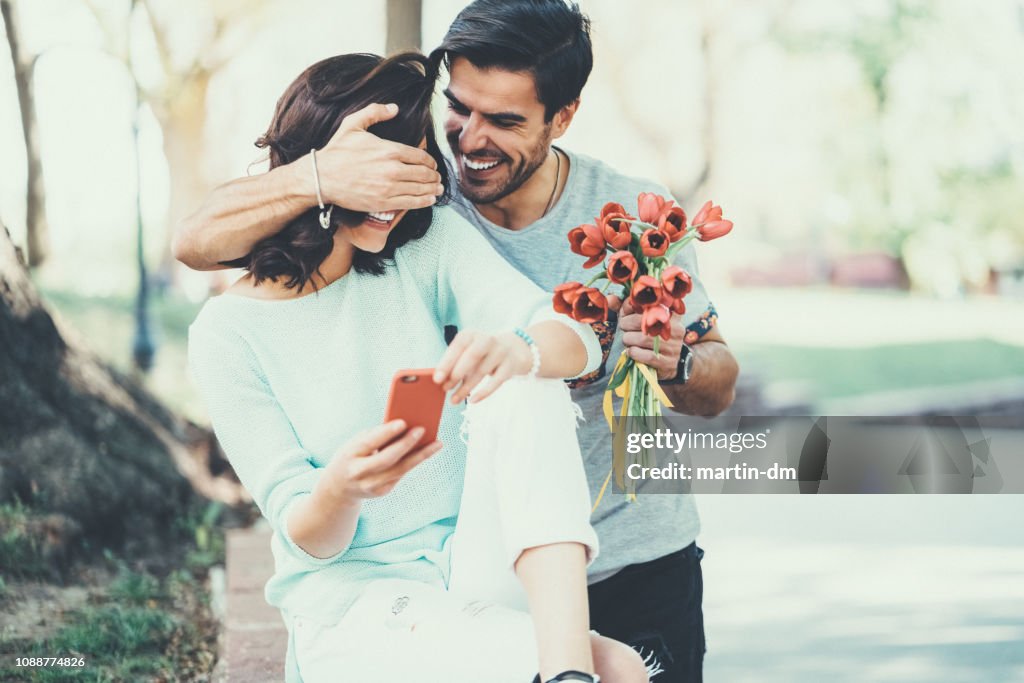Young man surprising his girlfriend with bouquet of tulips