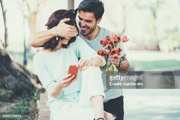 young man surprising his girlfriend with bouquet of tulips - valentines couple stock pictures, royalty-free photos & images