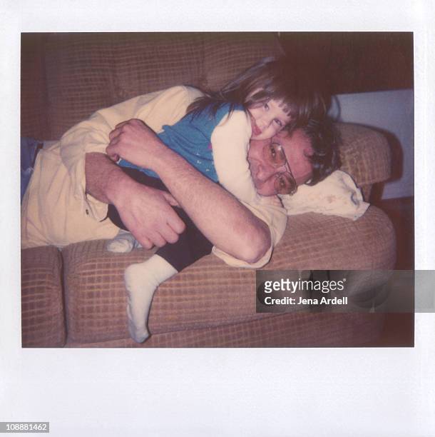 polaroid of father and daughter hugging on couch - di archivio foto e immagini stock