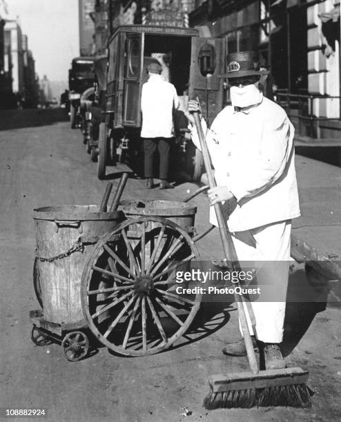 New York city street sweeper wears a mask to help check the spread of the influenza epidemic, October 1918. In the view of one official of the New...