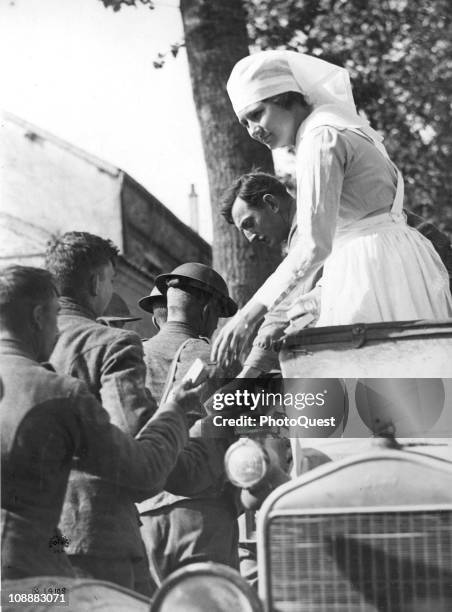 Miss Mary Withers of the American Red Cross hands out cigarettes and chocolate to soldiers of the American 2nd Battalion, 30th Infantry Regiment, 3rd...