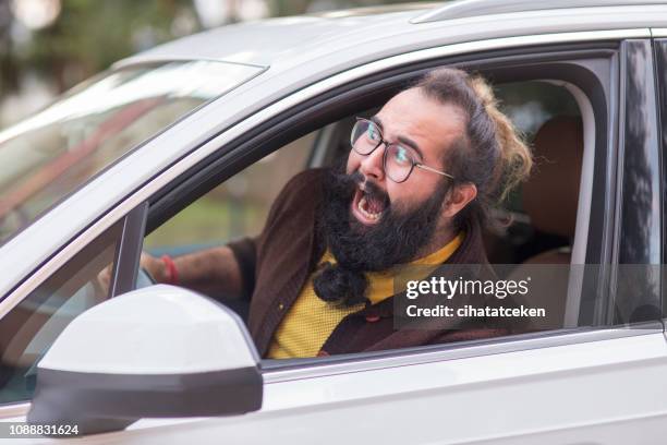 verärgerter mann hinter dem lenkrad zeigt wut im straßenverkehr - traffic jam stock-fotos und bilder