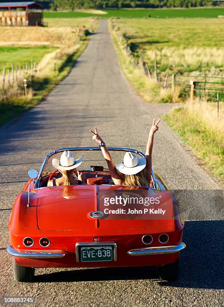 two women in red classic american car - red car stock pictures, royalty-free photos & images