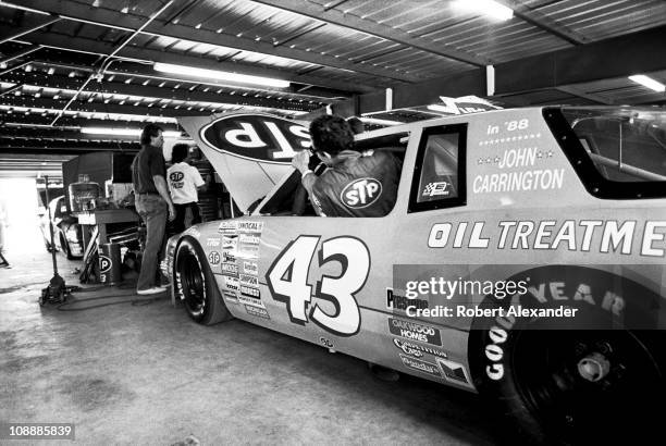 Richard Petty, driver of the STP Pontiac, climbs out of his car in the garage at Daytona International Speedway during qualifying for the 1988...