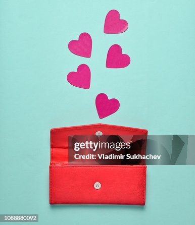 Rotem Leder Geldbörse mit dekorativen Herzen auf blauem Grund Pastell, Konzept der Liebe, Minimalismus Rotem Leder Geldbörse mit dekorativen Herzen auf blauem Grund Pastell, Konzept der Liebe, Minimalismus