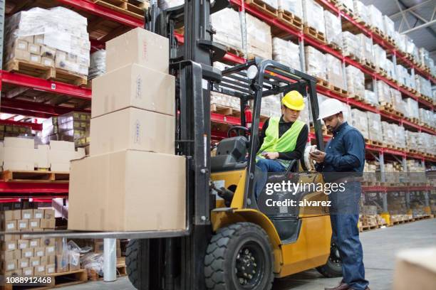 supervisor explicando los detalles de carga con operador de carretilla elevadora - carretilla elevadora fotografías e imágenes de stock