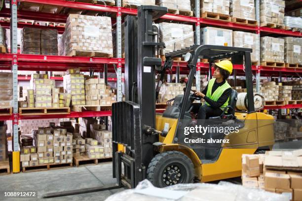 woman driving forklift in warehouse - forklift truck stock pictures, royalty-free photos & images