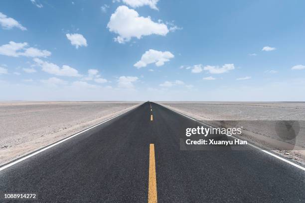 view along a straight asphalted road through desert - autostrada a due corsie foto e immagini stock