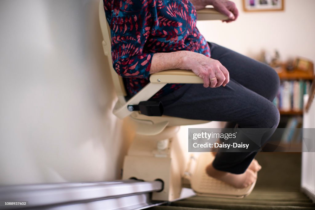 Detalle de mujer mayor sentada en la escalera ascensor en casa para ayudar a movilidad