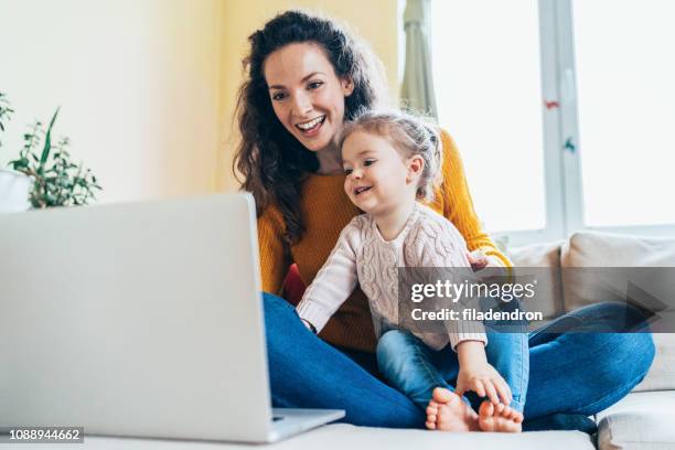 moeder en dochter kijken cartoons - mum sitting down with baby stockfoto's en -beelden