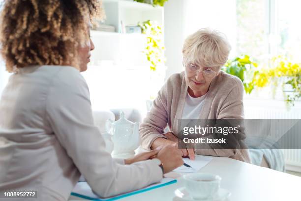 senior woman talking with insurance advisor - law problems stock pictures, royalty-free photos & images