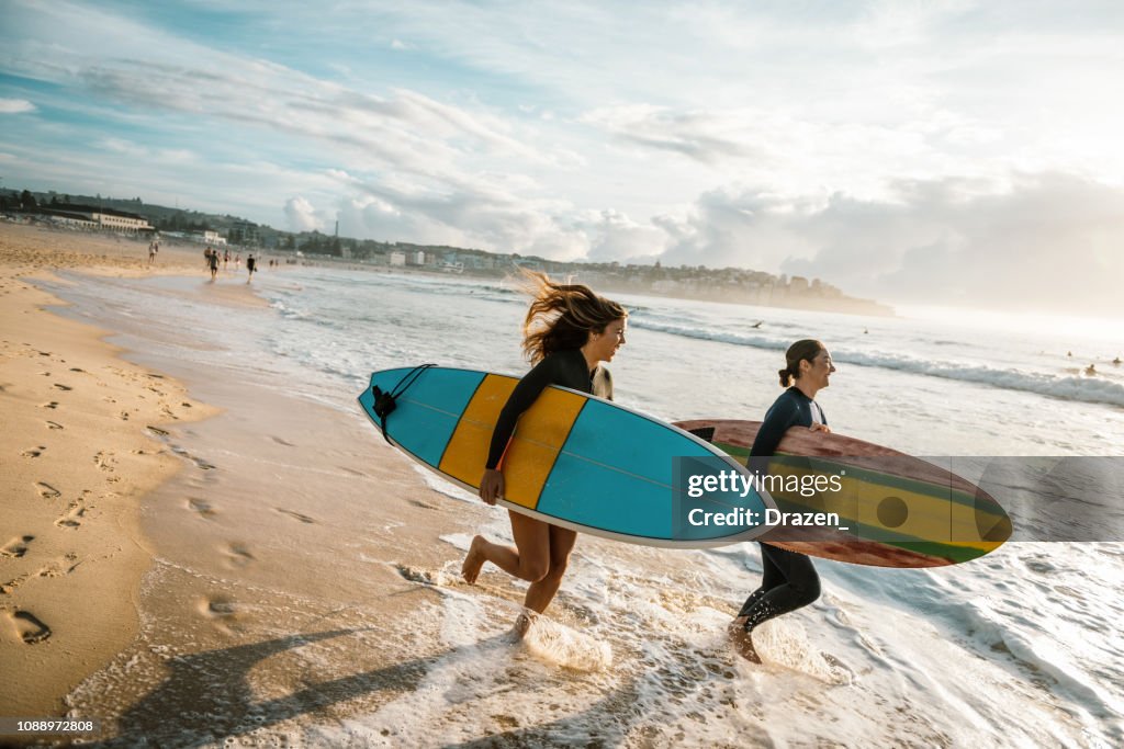 Dos mujeres jóvenes en trajes de neopreno para hacer surf