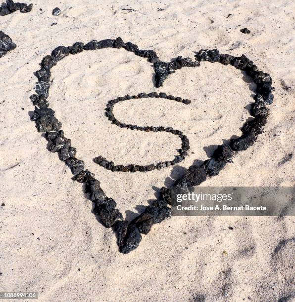 painted heart in the sand with volcanic stones. chinijo natural park, graciosa island, canary islands, spain. - letter s stock pictures, royalty-free photos & images