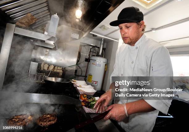 RollinGreens co-owner and chef Ryan O. Cunningham flips some burgers on Thursday, March 8, while serving lunch from the RollinGreens food truck in...