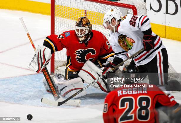 Miikka Kiprusoff of the Calgary Flames makes a save on Troy Brouwer of the Chicago Black Hawks in third period action at Scotiabank Saddledome...