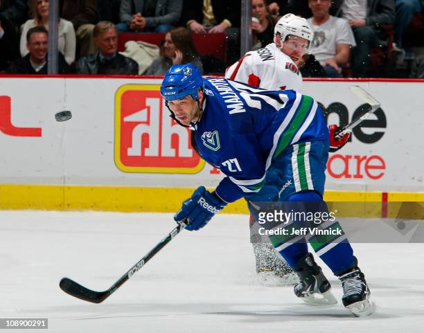 Manny Malhotra of the Vancouver Canucks and Daniel Alfredsson of the Ottawa Senators watch a loose puck during their game at Rogers Arena on February...