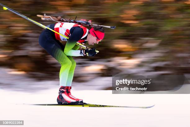 side view of male biathlon competitor at cross-country skiing, motion blurred - biathlon ski stock pictures, royalty-free photos & images