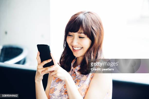 アジアの女性の携帯電話に - 若い女性 日本人 顔 ストックフォトと画像