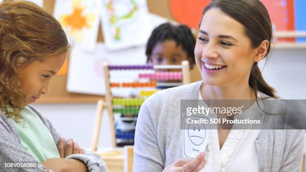 young, female teacher smiles at student while holding flashcard - flash card stock pictures, royalty-free photos & images