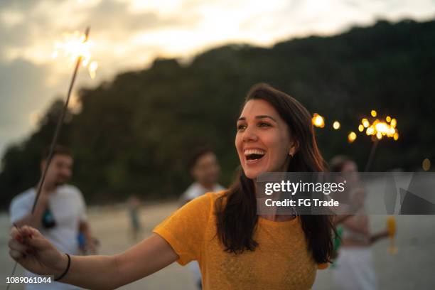 mujer celebrando el año nuevo en la playa con luces de bengala - wish fotografías e imágenes de stock